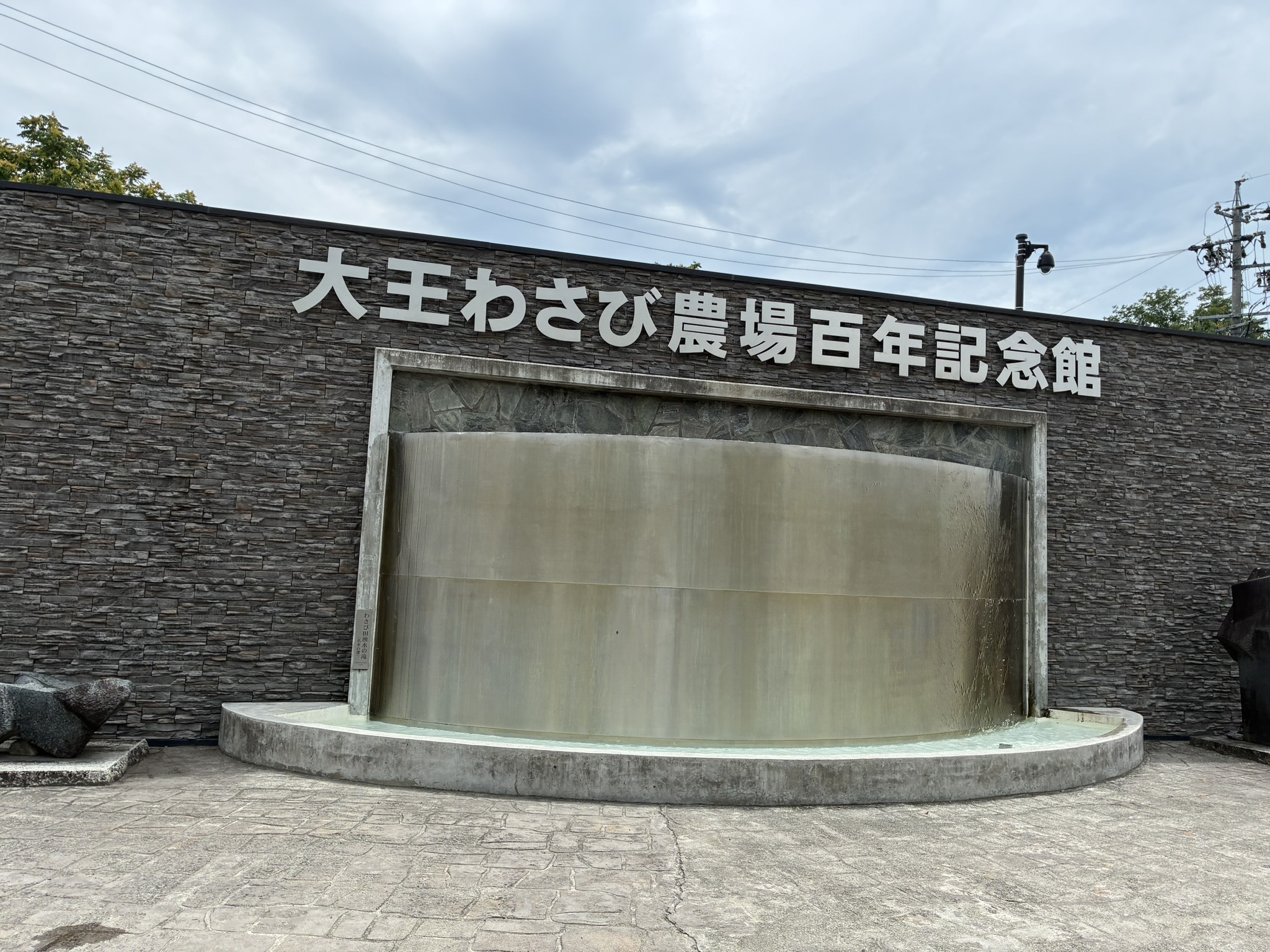 大王わさび農場百年記念館の名称が掲げられた水の壁