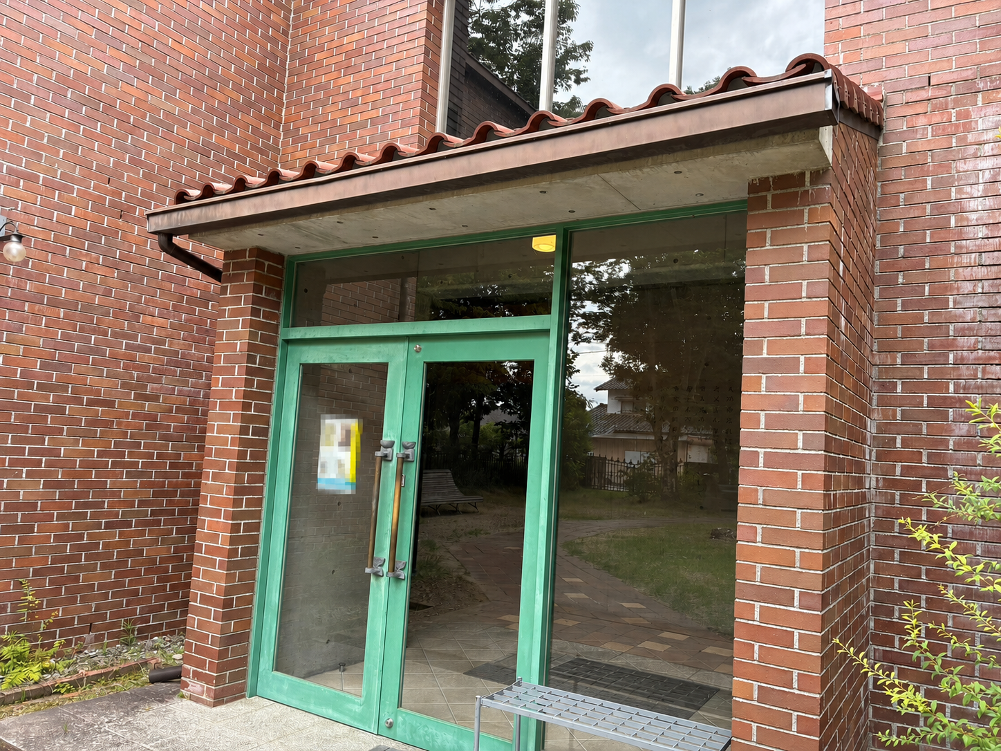 赤レンガの外壁と緑色の扉がある碌山美術館の杜江館