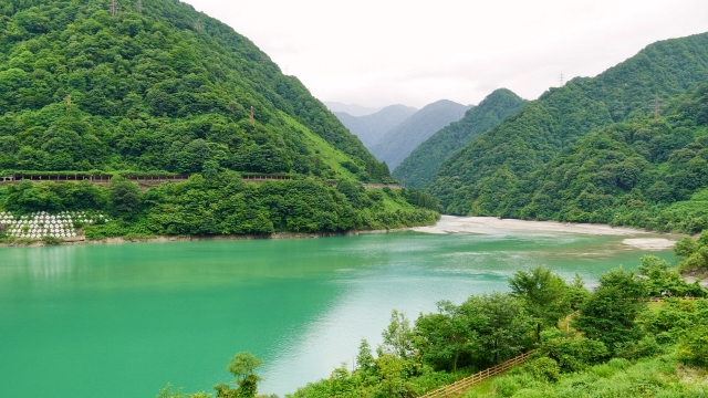 緑の山々に囲まれた黒部峡谷のエメラルドグリーンの湖