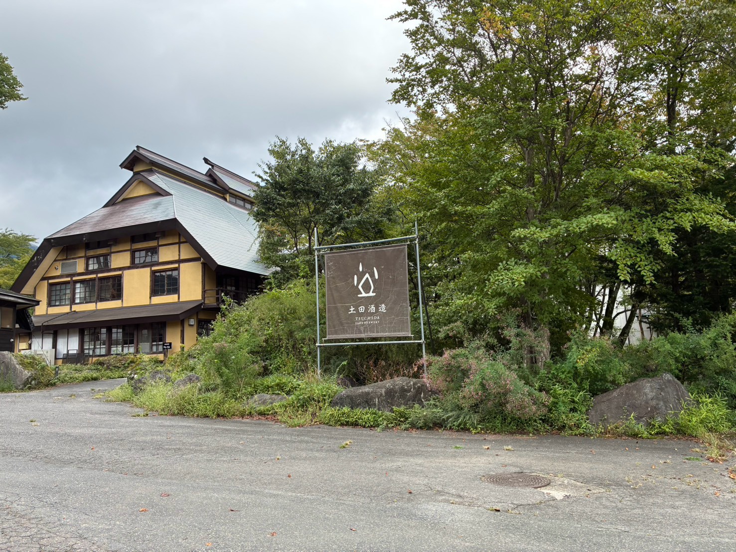土田酒造の看板と木々に囲まれた建物外観